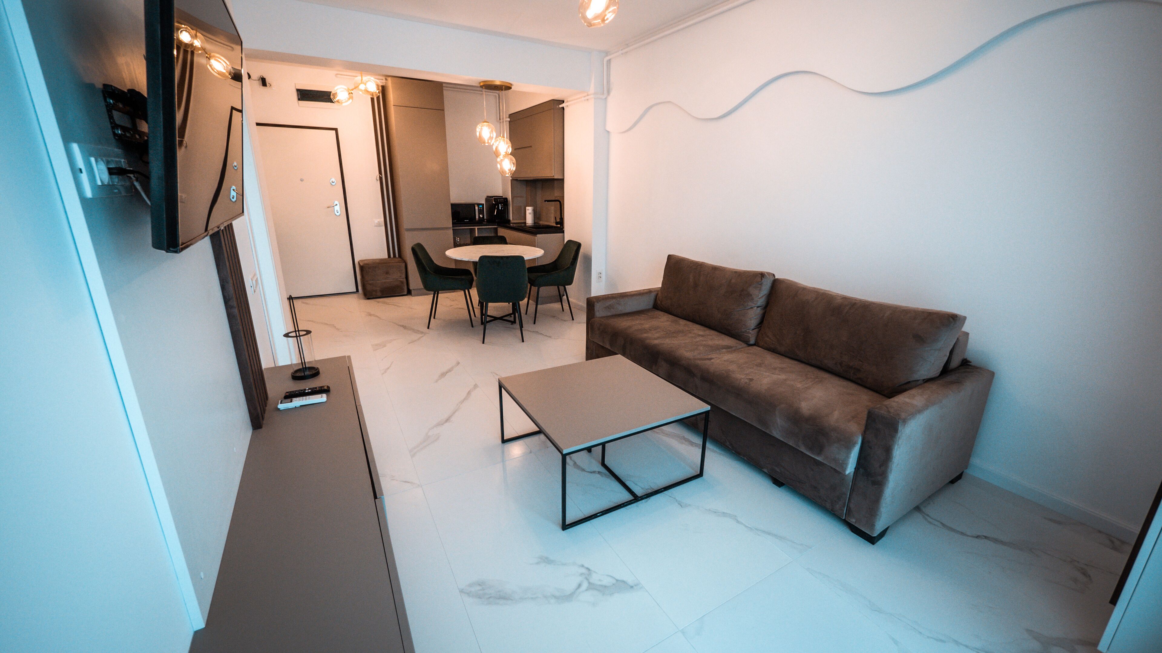 A modern living room with a sofa, coffee table, and dining area.
