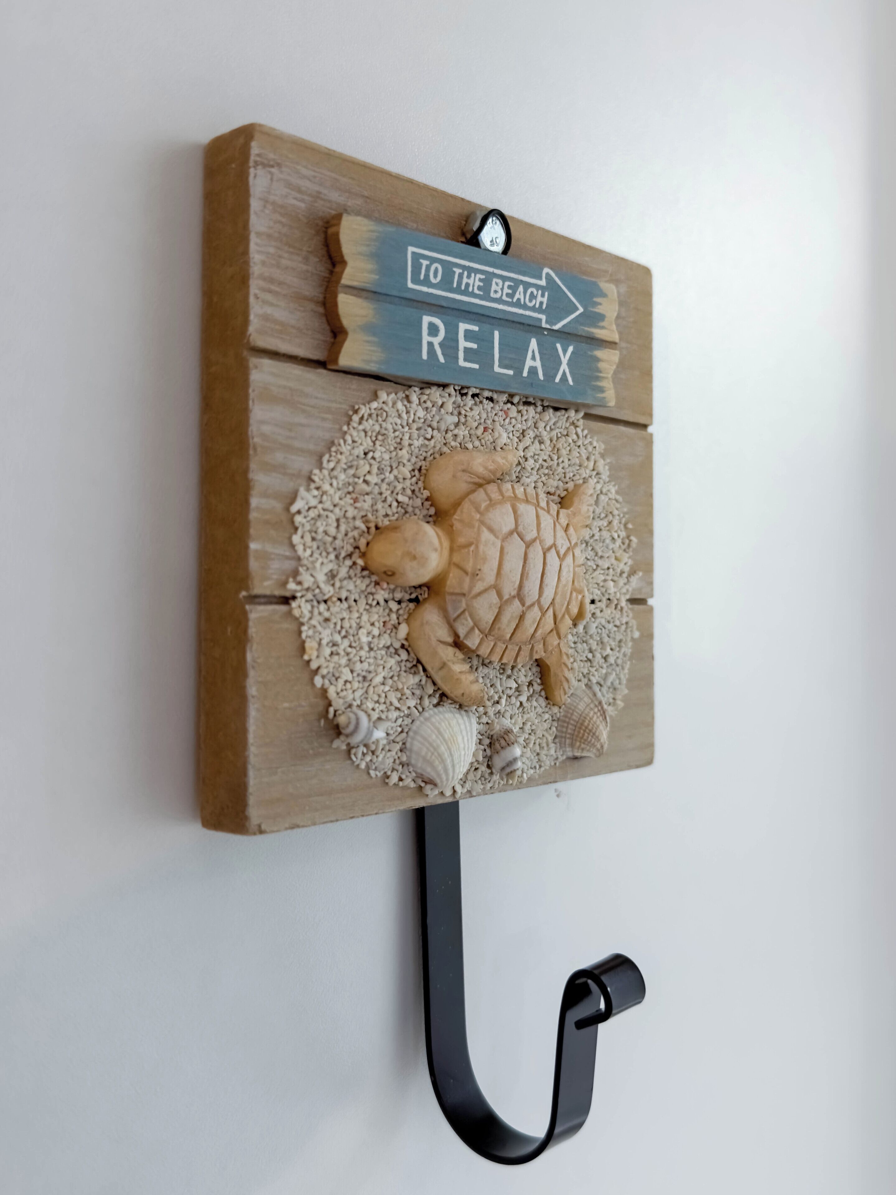 A wooden wall-mounted sign with a turtle and the words "TO THE BEACH RELAX" on it.