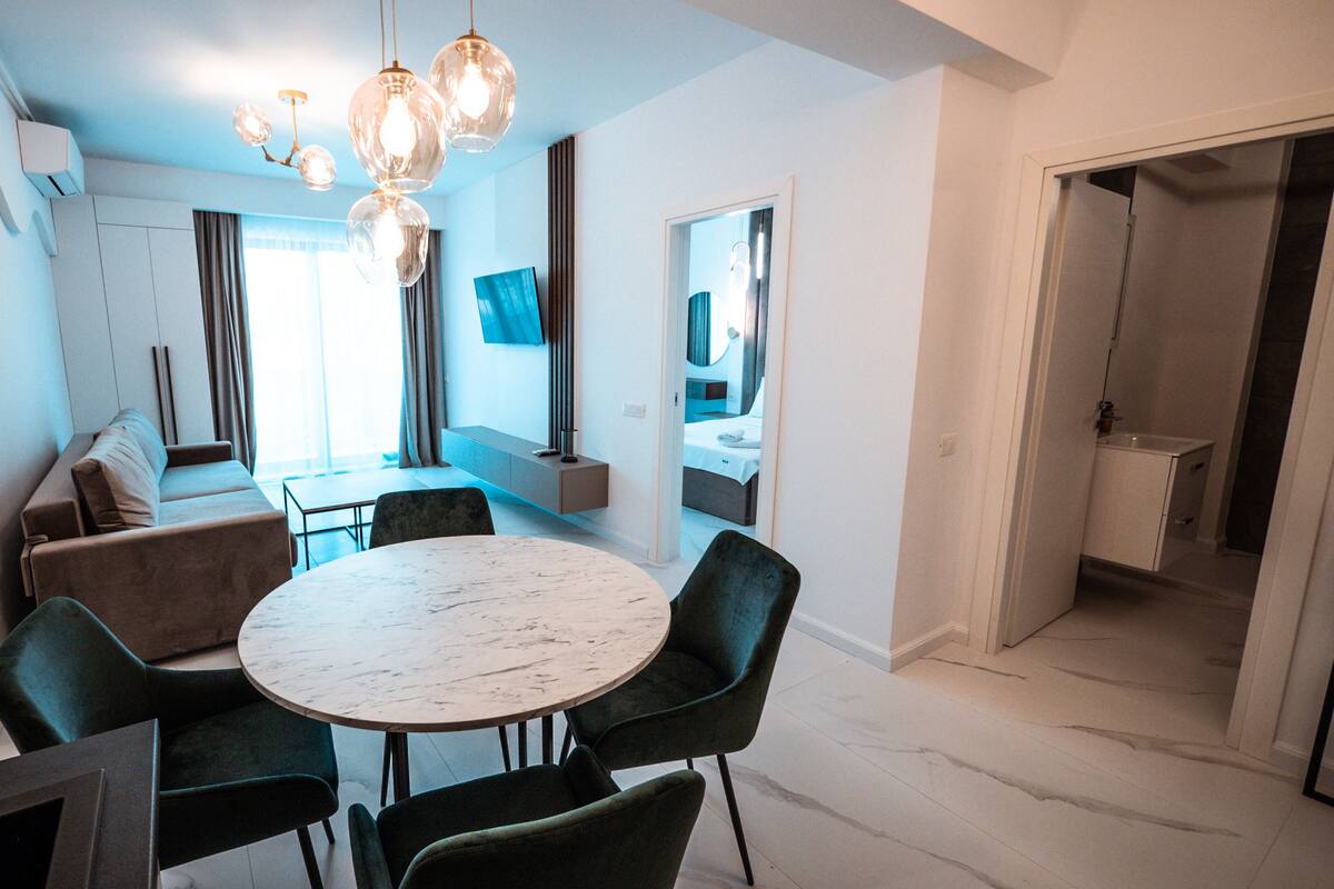 Un comedor moderno con una mesa redonda y sillas, un sofá y un televisor montado en la pared.