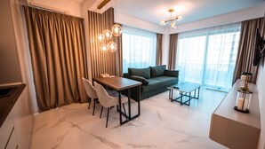 A modern living room with a sofa, a dining table with chairs, a coffee table, and a chandelier. - Wave 4 Residence (Navodari)