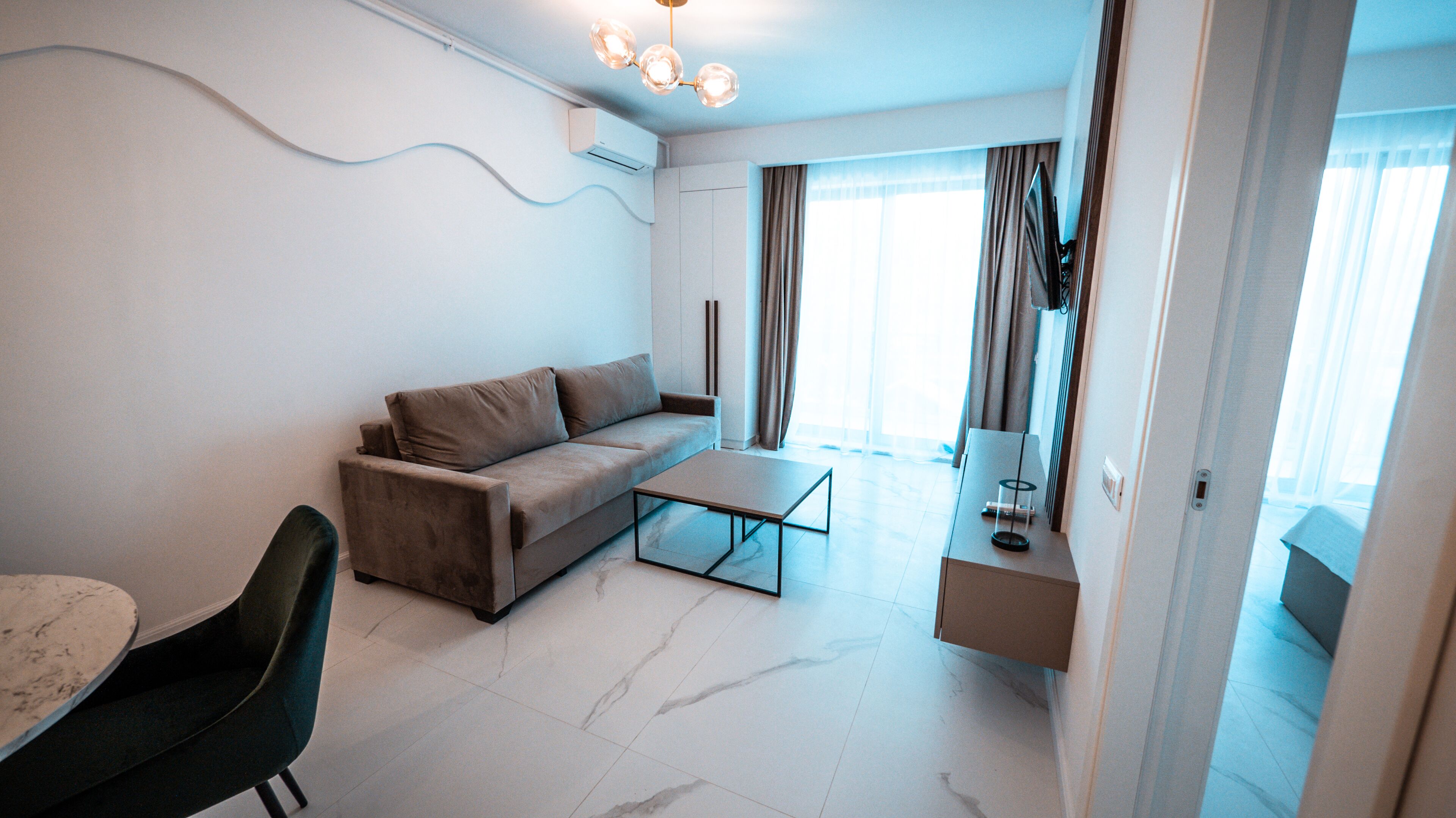 A modern living room with a sofa, coffee table, and a dining area with a table and chairs.