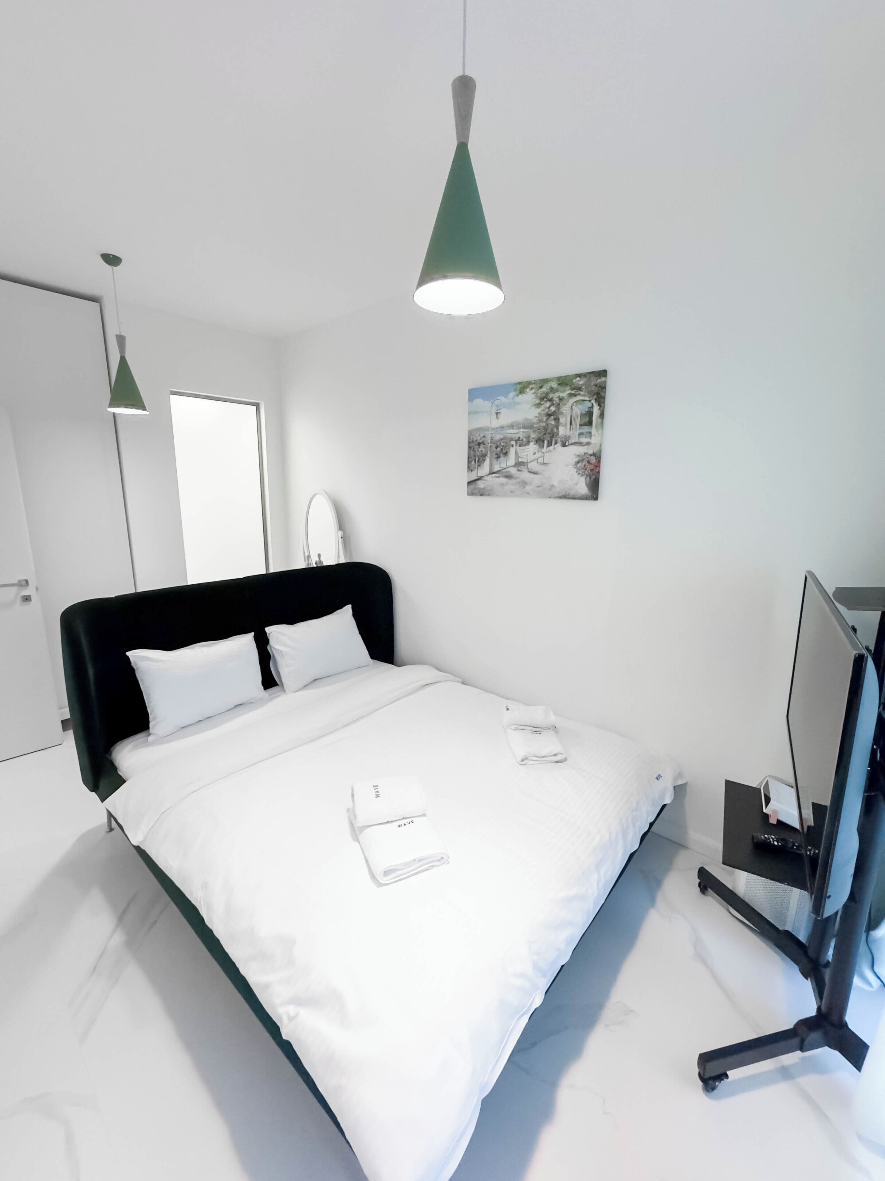 Una habitación de hotel moderna con cama, escritorio, silla, televisor y un cuadro en la pared.