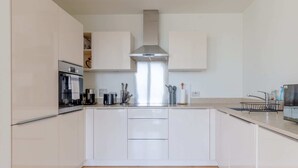 Une cuisine moderne avec des meubles blancs, une hotte en acier inoxydable et un îlot central.