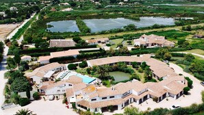 Un hotel con diseño circular, múltiples piscinas y un entorno que incluye cuerpos de agua y abundante vegetación.