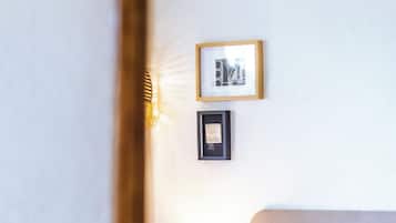 Un lit bien fait, avec des oreillers et une couverture, une lampe de chevet et deux tableaux encadrés accrochés au mur.