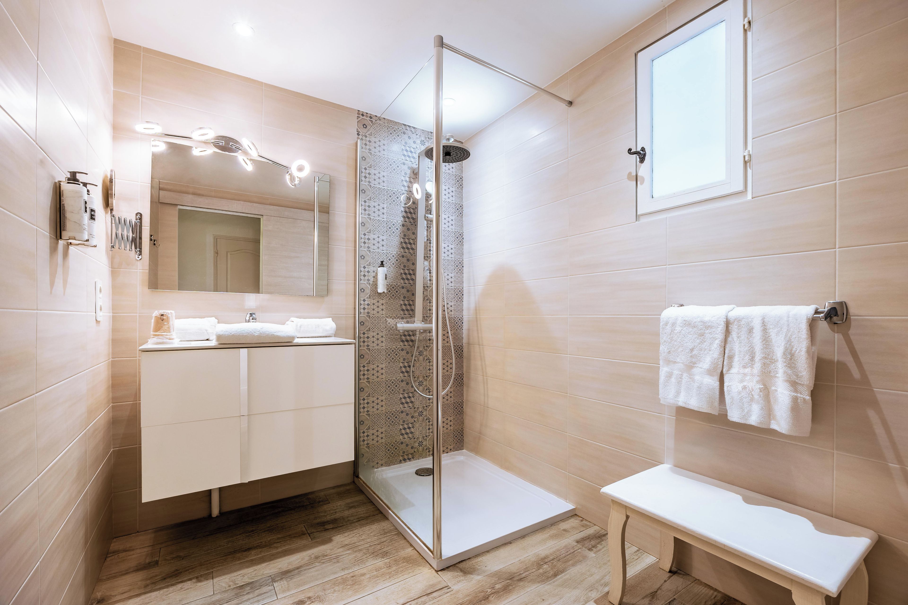 A modern bathroom with a glass-enclosed shower, a vanity with a mirror, and a towel rack.
