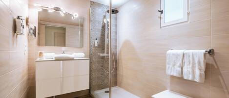 A modern bathroom with a glass-enclosed shower, a vanity with a mirror, and a towel rack.