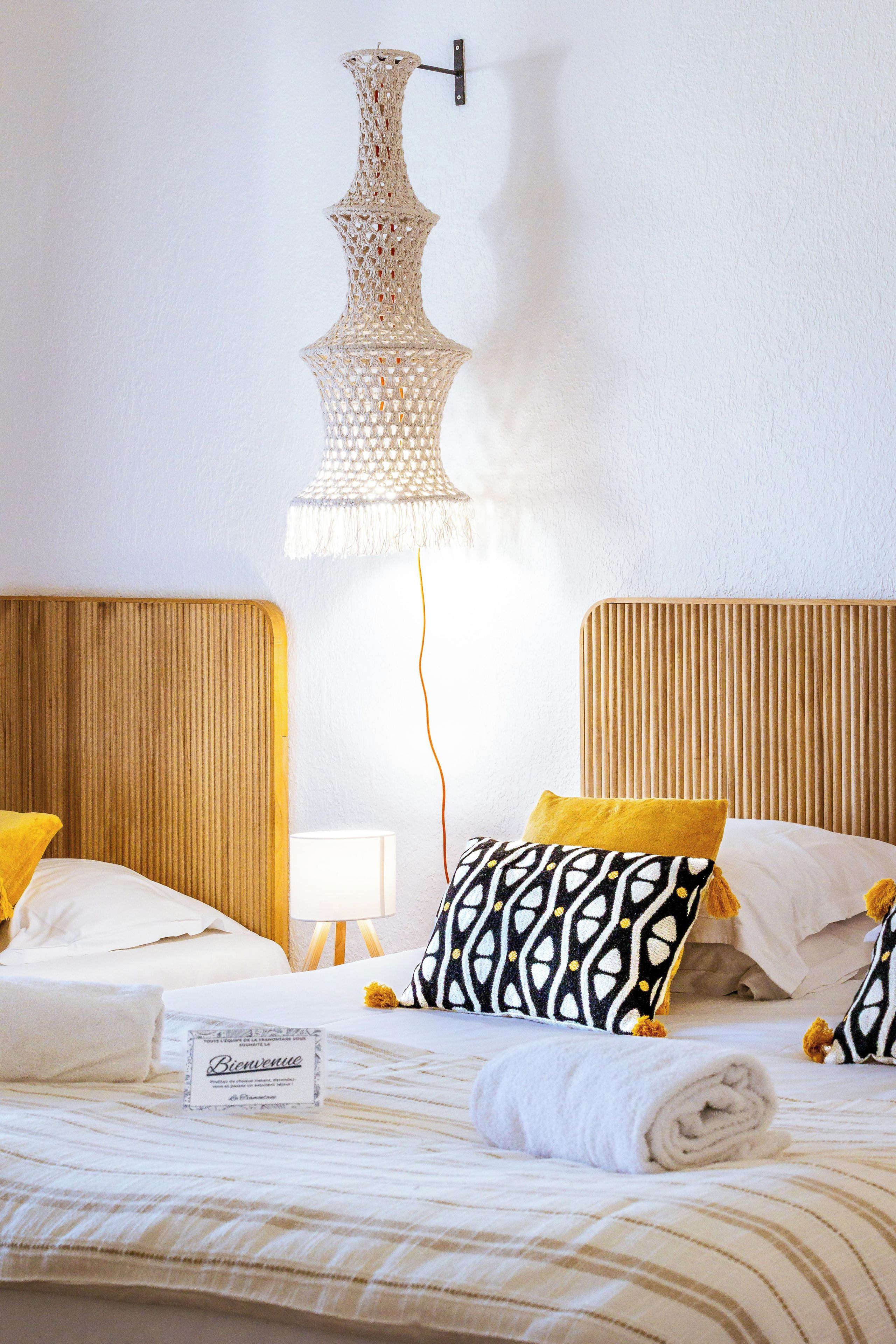 A hotel room with two beds, a decorative hanging light fixture, and a sign on the bed.