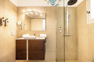 Un baño moderno con tocador, espejo y ducha.