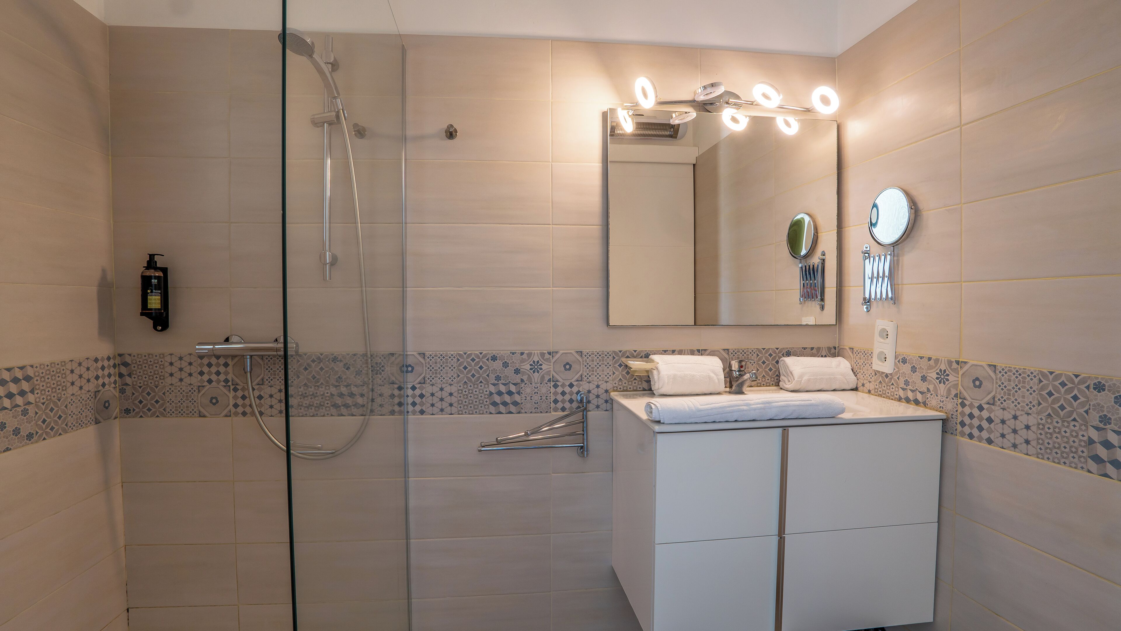 A modern bathroom with a glass shower enclosure, a white vanity with a mirror, and a tiled backsplash.