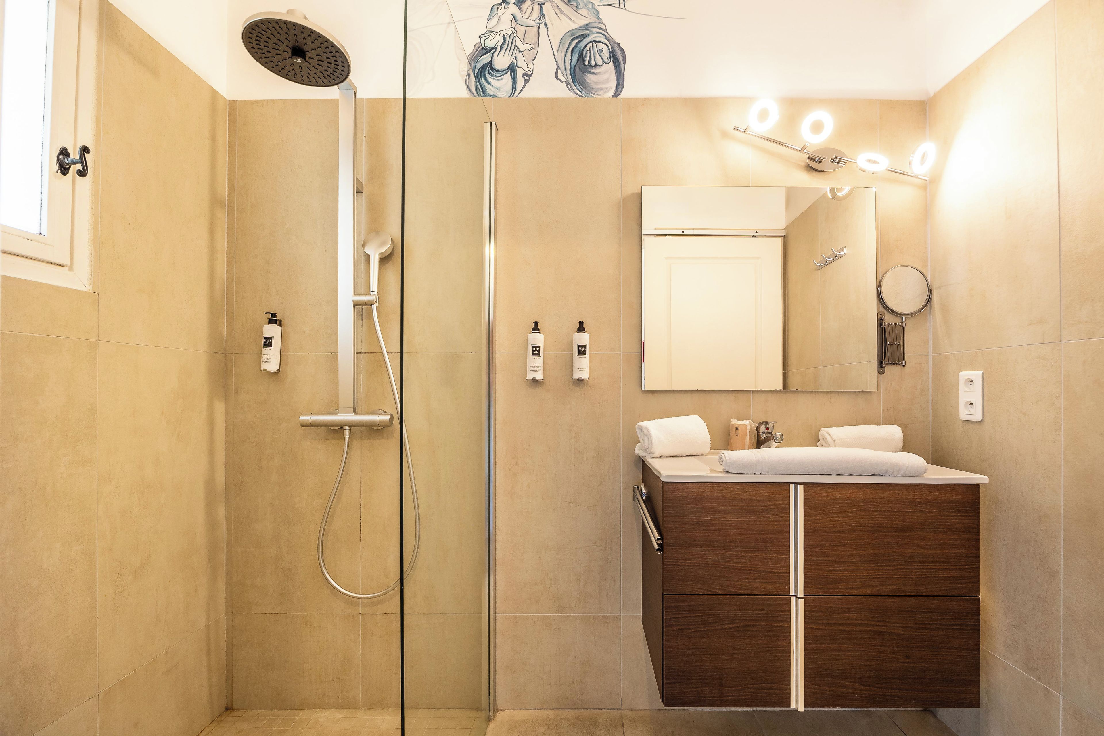 Un baño moderno con ducha envuelta en vidrio, tocador con espejo y perchero para toallas.