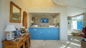 A reception area with a wooden desk, a blue counter, a mirror, and a television screen.
