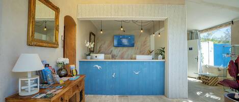 A reception area with a wooden desk, a blue counter, a mirror, and a television screen.