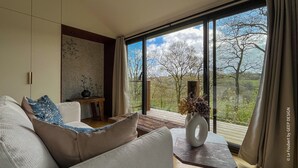 Una sala de estar moderna con un ventanal grande, un sofá, una mesita y un jarrón decorativo.
