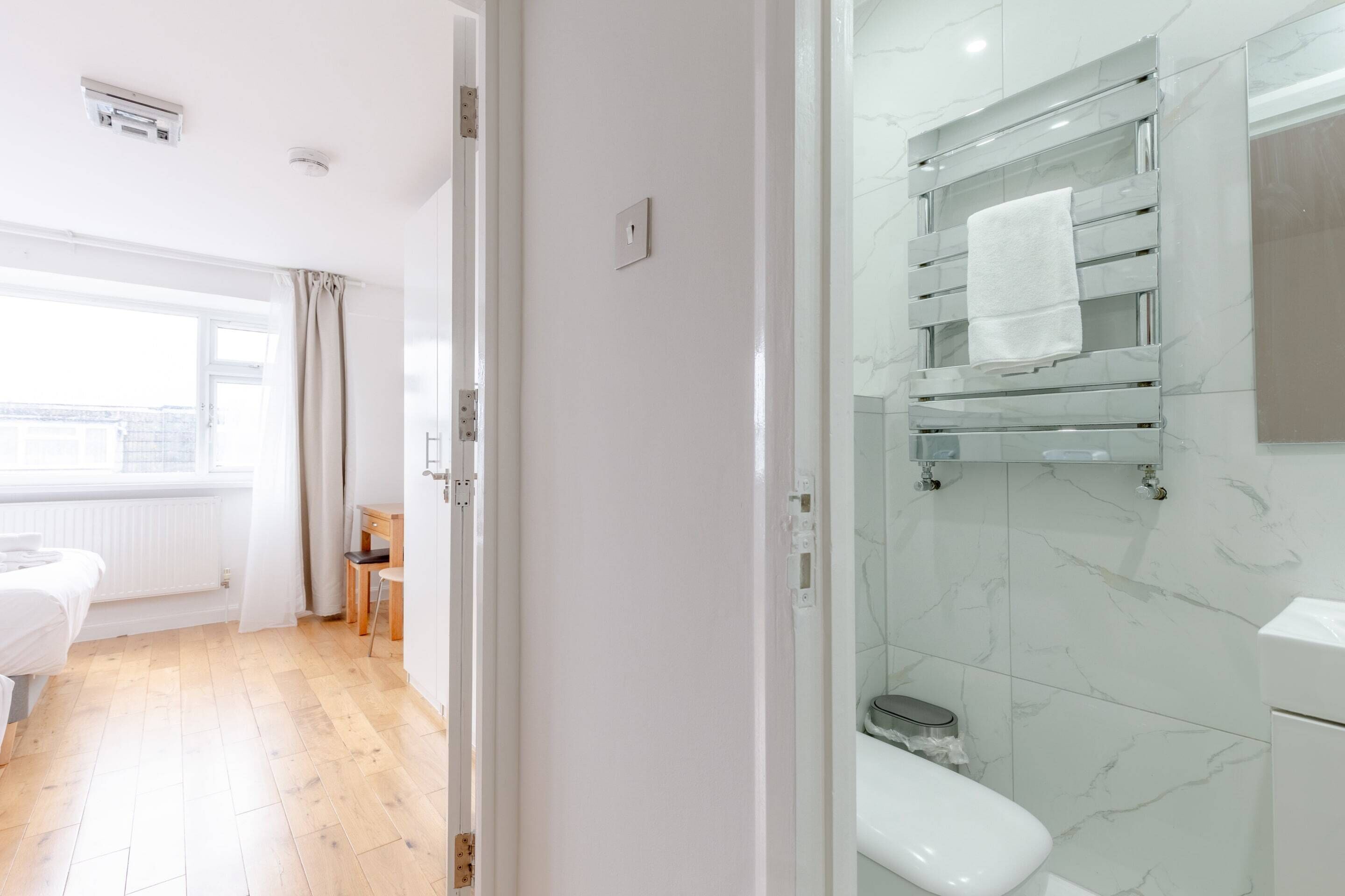 A modern bathroom with a toilet, a glass shelf with a towel, and a shower area.