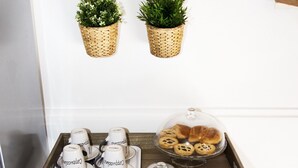 A small wooden table with a tray holding teacups, cookies, and a photo frame. - Casa Delle Mancarelle (Syracuse)