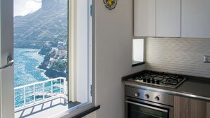 A kitchen with a view of the sea, a stove, and cabinets. - L'Aurora house with sea view, WIFI, air conditioning, on the path of the Lemons (Minori)