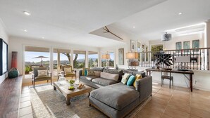 A spacious living room with a large sectional sofa, a coffee table, and a view of the outdoors. - Gorgeous Pool and Sweeping Views (Sonoma)