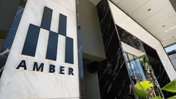 Un edificio moderno con un llamativo letrero 'AMBER' sobre una columna de mármol blanco.