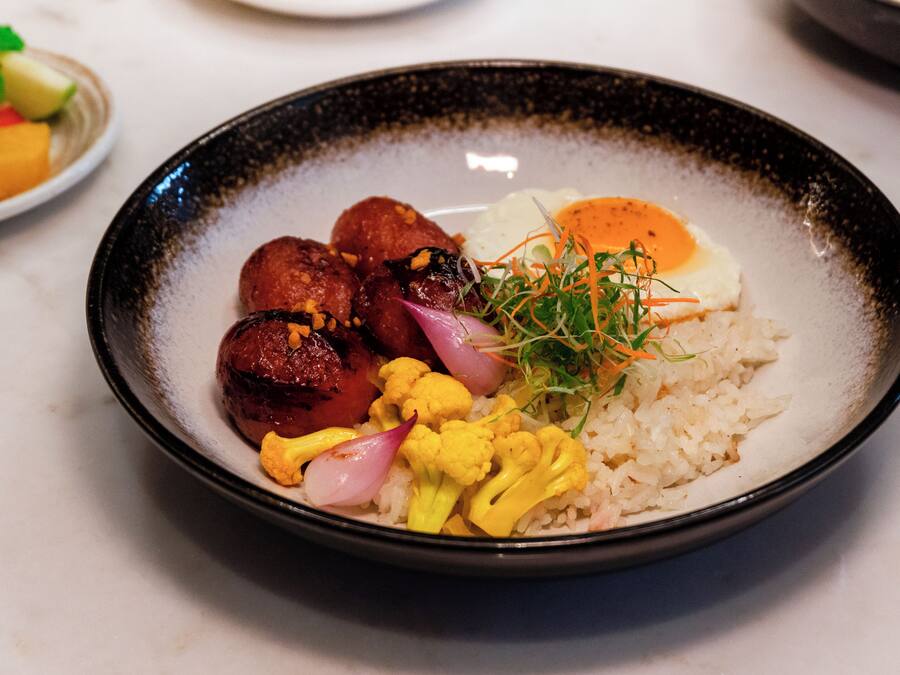 Une assiette de nourriture composée de riz, de légumes et d’un œuf poché.