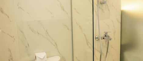 A modern bathroom with a glass-enclosed shower, a toilet, and marble walls.