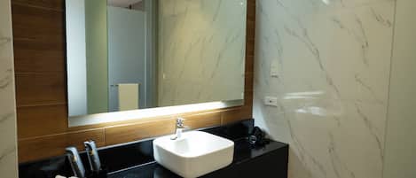 A modern bathroom with a marble sink, a large mirror, and a wooden vanity.