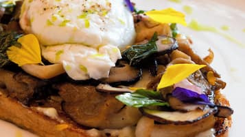 A dish with poached eggs, mushrooms, and greens on toast, served on a white plate.
