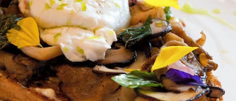 Un plato con huevos escalfados, setas y verduras sobre tostada.