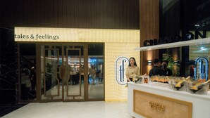 En hotelindgang med et skilt der siger "tales & feelings" og en disk med kurve mærket "Garden Spritz".