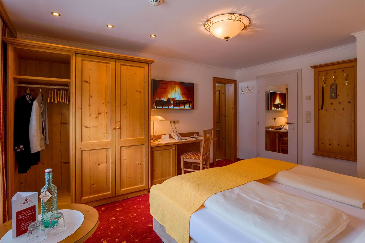 A hotel room with a bed, a desk, a chair, a wardrobe, and a television.