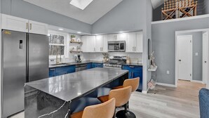 A modern kitchen with a central island, stainless steel appliances, and blue cabinets. - Pocono Blue | Paddleboards, Spa, Indoor Jacuzzi, GameRoom, Lake, EV (Clifton Township)