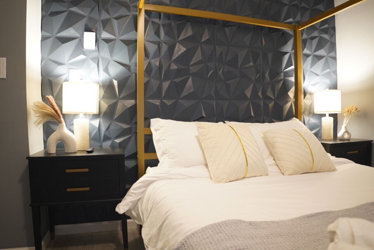 A four-poster bed with a geometric-patterned wall behind it.