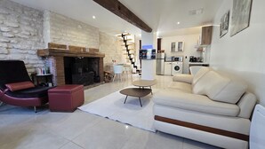Un salon moderne avec une cheminée, un canapé, un fauteuil rouge et une table basse.