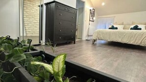 Une chambre à coucher avec un lit, une commode et une grande fenêtre.