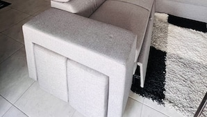 Een moderne woonkamer met een modulaire bank, een vloerkleed en een kunstwerk aan de muur.