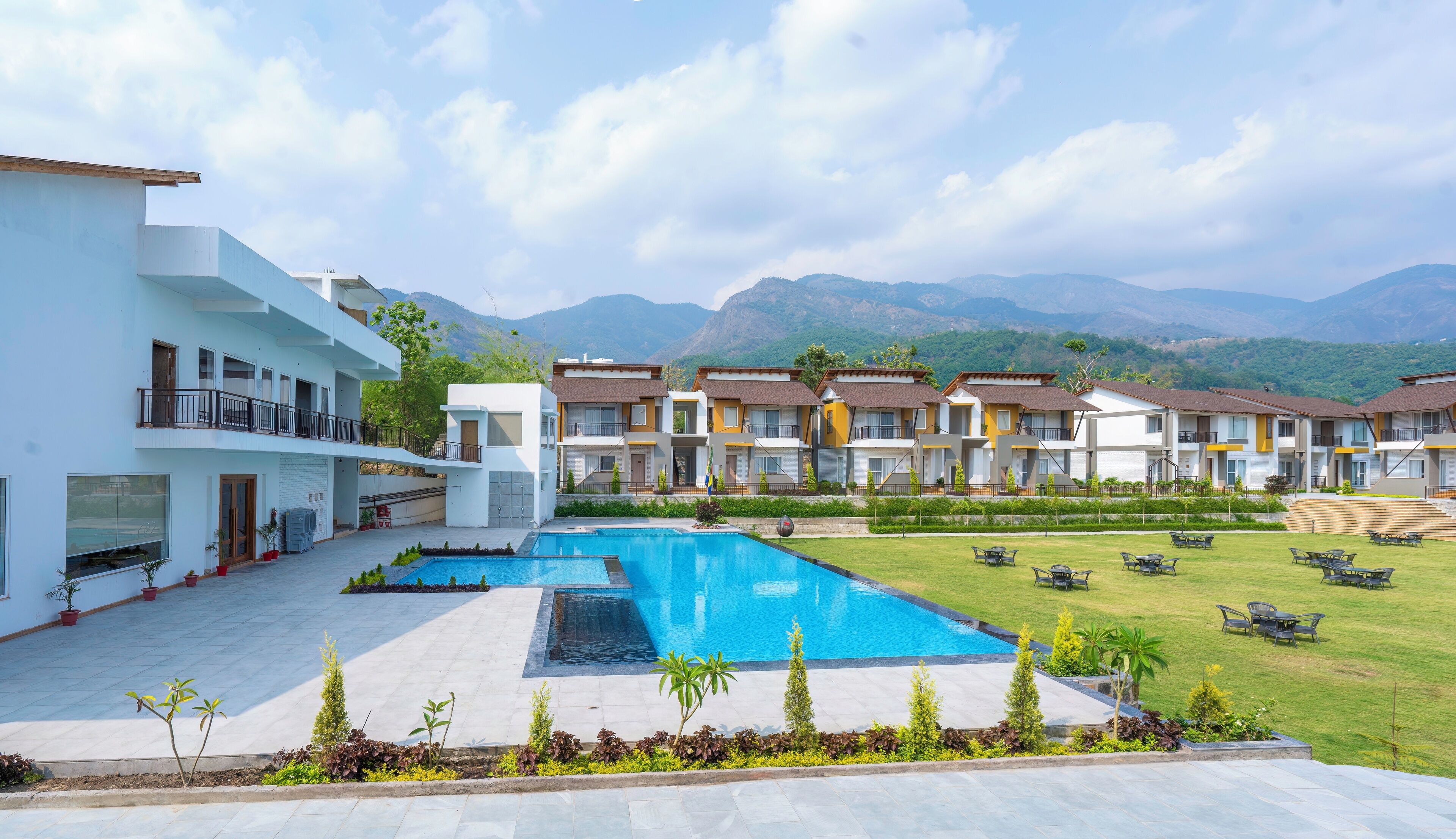 Un hotel con piscina, zona de estar exterior y vistas a las montañas.