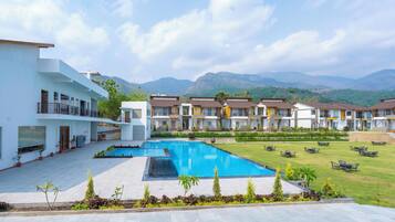 Un hotel con piscina, zona de estar exterior y vistas a las montañas.