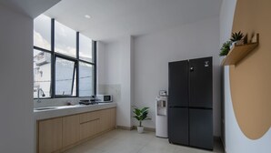 Una cocina moderna con un ventanal grande, un refrigerador negro y una planta pequeña.
