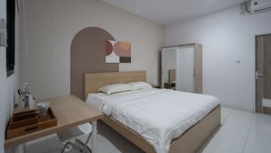 Un dormitorio con cama, escritorio, silla, armario y una obra de arte colgada en la pared.