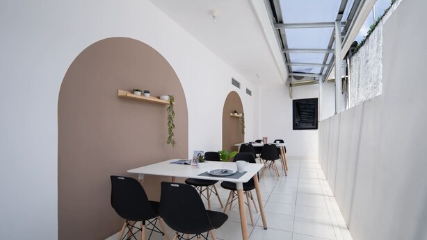 Un comedor moderno con una mesa blanca, sillas negras y techo de cristal.