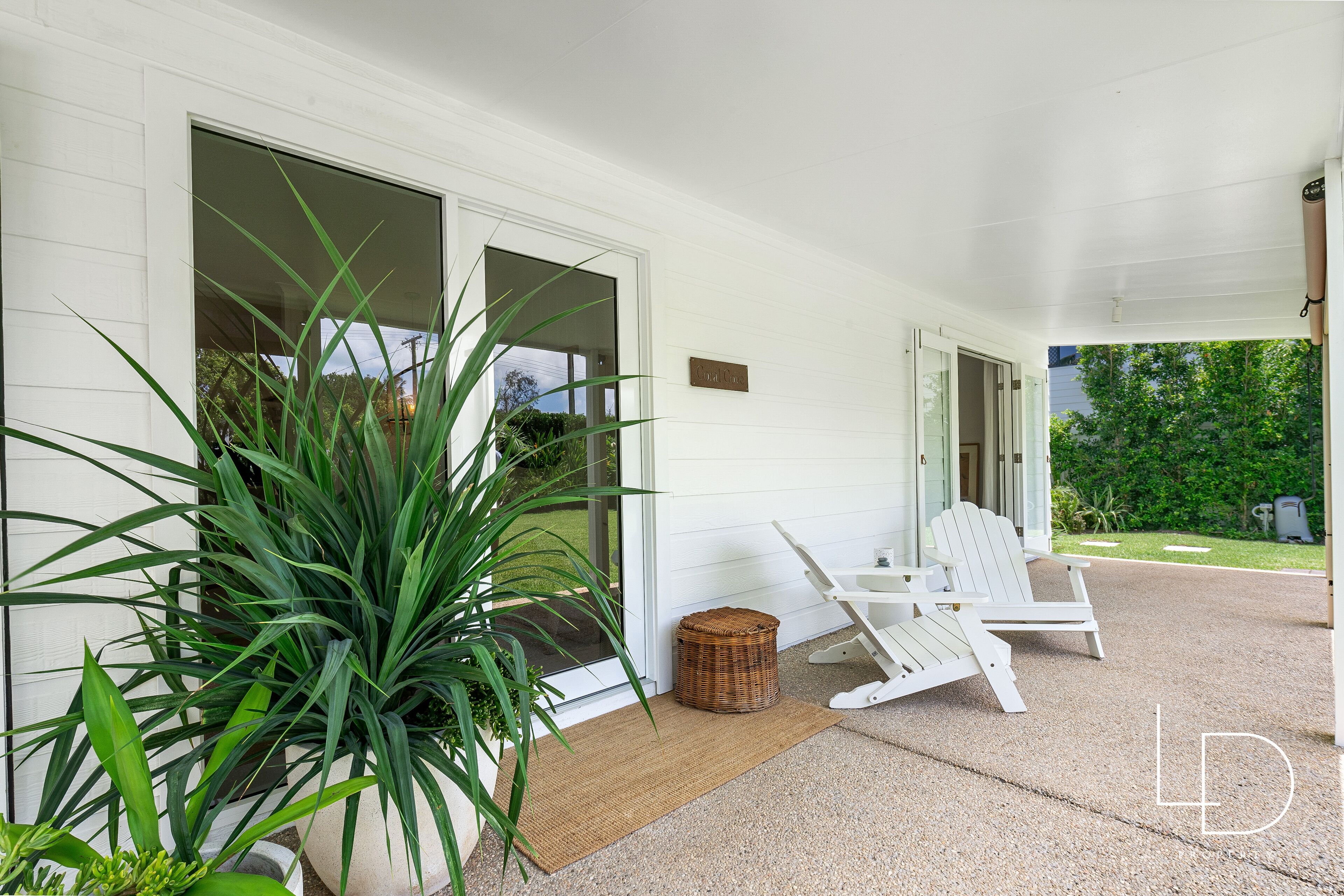 A covered porch with a white chair and a wicker basket.