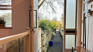 Un intérieur moderne avec un plancher en bois, un banc, une porte donnant sur l’extérieur et une vue sur un jardin.