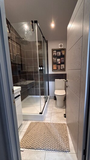 Een moderne badkamer met een douchecabine van glas, een toilet en een luchtzuiveraar aan de muur.
