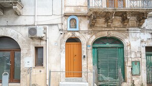 A building facade with a wooden door, a green shutter door, and a small window with a religious icon. - Elegance Staffa Rooms (Carovigno)