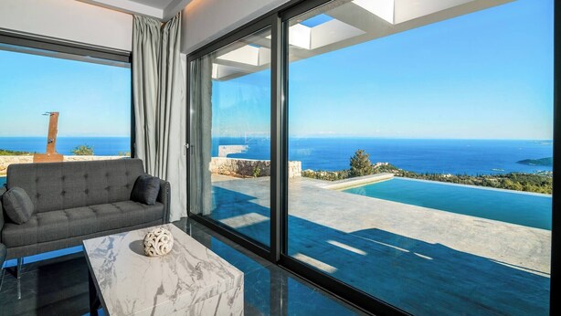 A modern room with a large window, a sofa, and a marble table. - Nikolakos Villa - Pirvate Pool (Zakynthos)