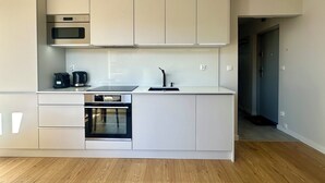 A modern kitchen with white cabinetry, a built-in oven, a microwave, and a coffee maker. - Apartament Suzanne by Q4Apartments  (Wladyslawowo)