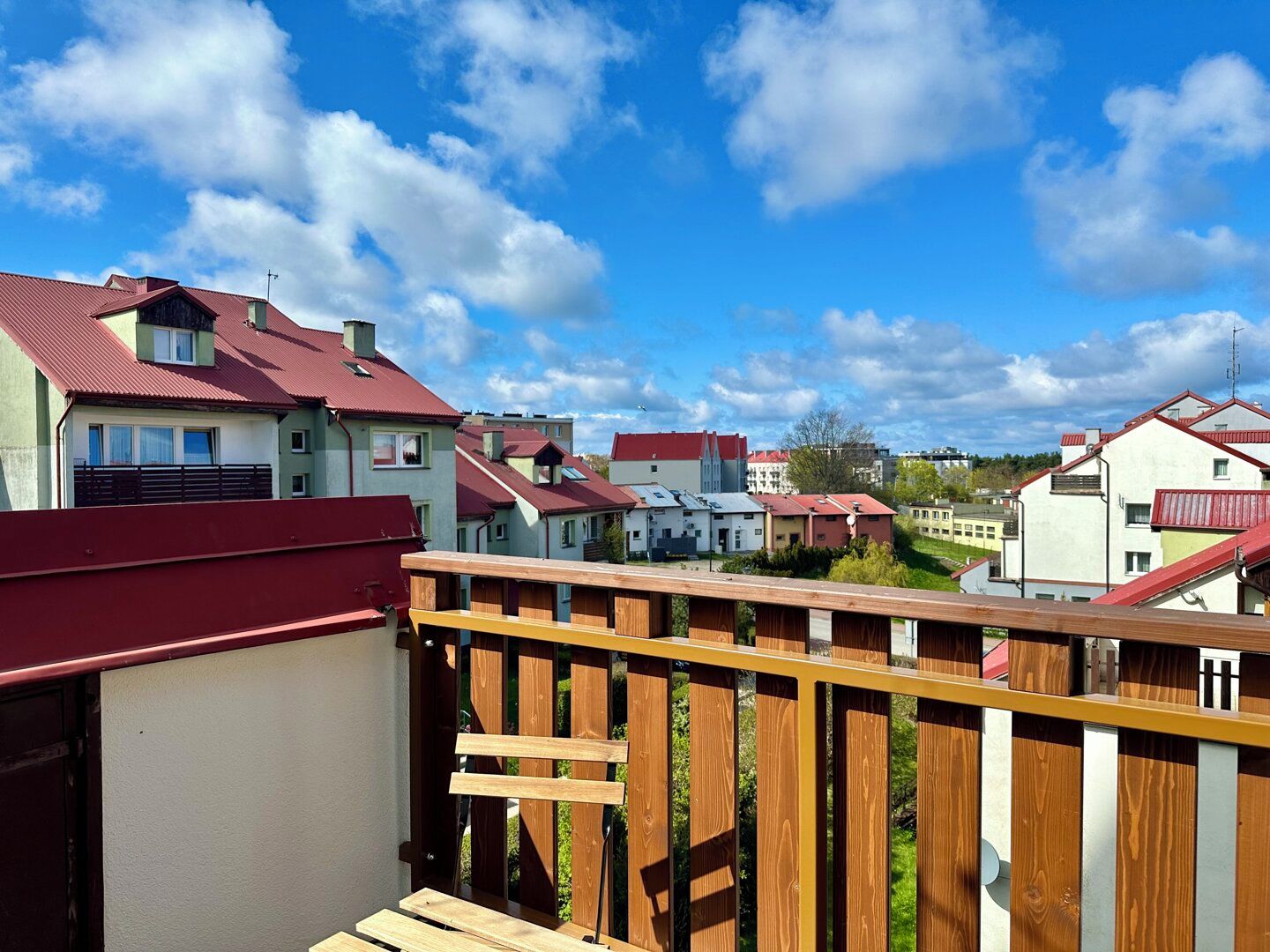 Bairro residencial com casas de telhados vermelhos e uma cerca de madeira em primeiro plano.