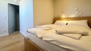 A modern bedroom with a wooden bed, a skylight, and a wall-mounted light fixture. - Apartament Suzanne by Q4Apartments  (Wladyslawowo)
