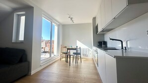 A modern kitchen with white cabinets, a black countertop, and a window overlooking a balcony. - Apartament Suzanne by Q4Apartments  (Wladyslawowo)