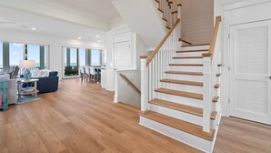 Un vaste espace de vie agrémenté d’un escalier en bois, de grandes fenêtres et d’une vue sur l’extérieur.
